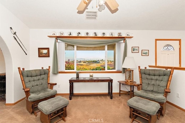 sitting room with carpet, arched walkways, a ceiling fan, visible vents, and plenty of natural light