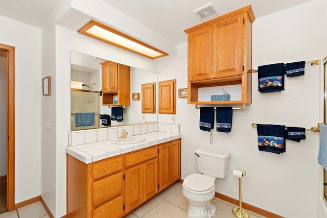 bathroom with a shower with door, toilet, vanity, and tile patterned floors