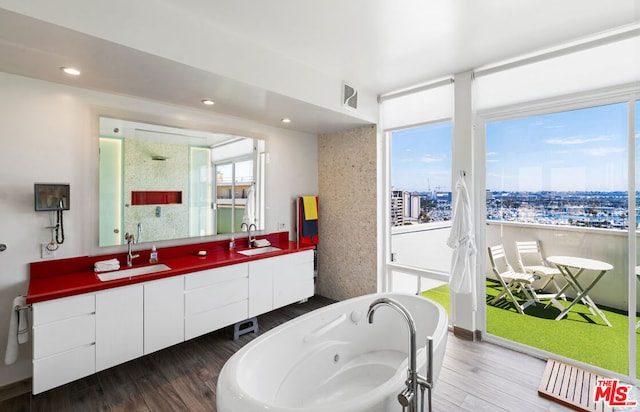 bathroom featuring hardwood / wood-style flooring, a tub to relax in, and vanity