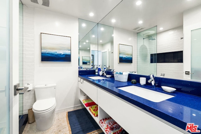 bathroom with tile patterned flooring, vanity, a tile shower, and toilet