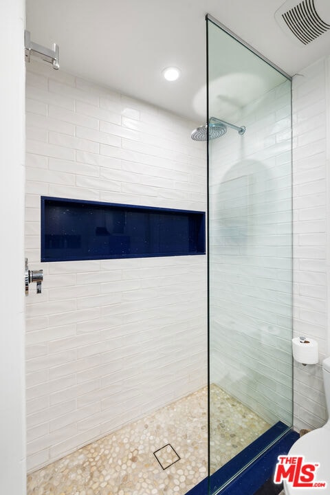 bathroom featuring tiled shower and toilet