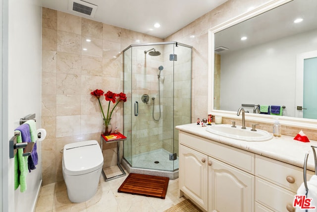 bathroom featuring vanity, toilet, a shower with door, and tile walls