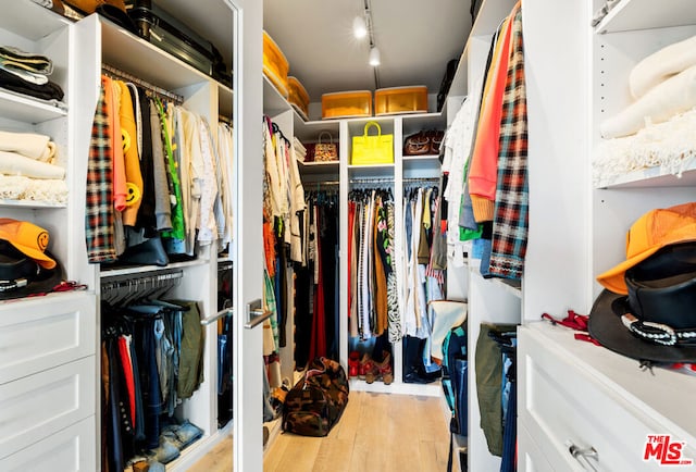 walk in closet with light hardwood / wood-style floors