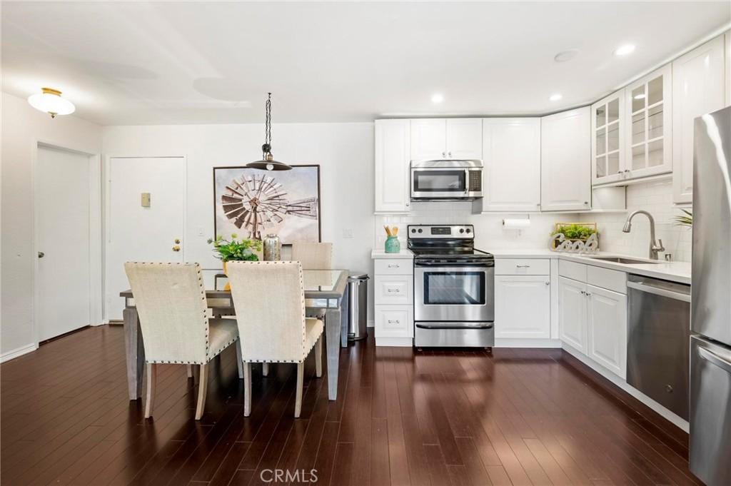 kitchen with white cabinetry, sink, dark hardwood / wood-style floors, decorative light fixtures, and appliances with stainless steel finishes