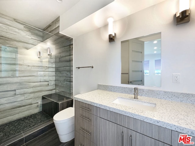 bathroom featuring vanity, toilet, and tiled shower