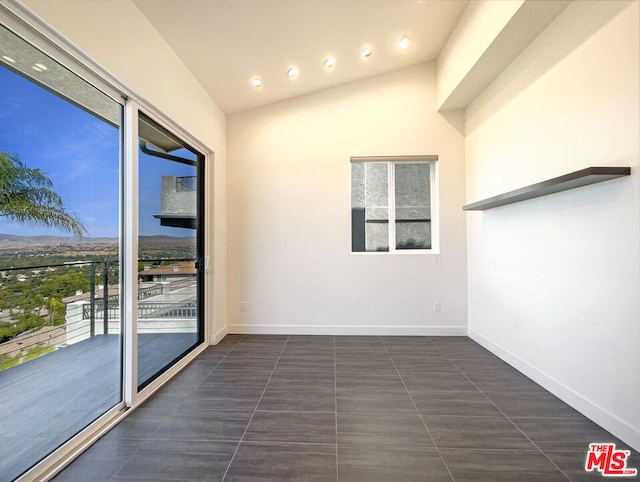 interior space with dark tile patterned floors and vaulted ceiling