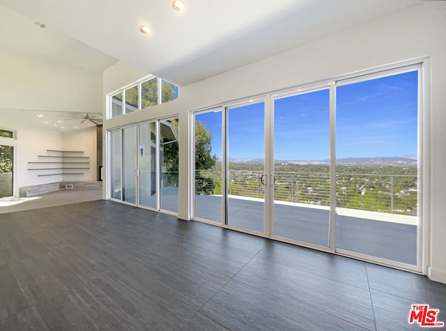 unfurnished living room featuring ceiling fan and dark wood-type flooring