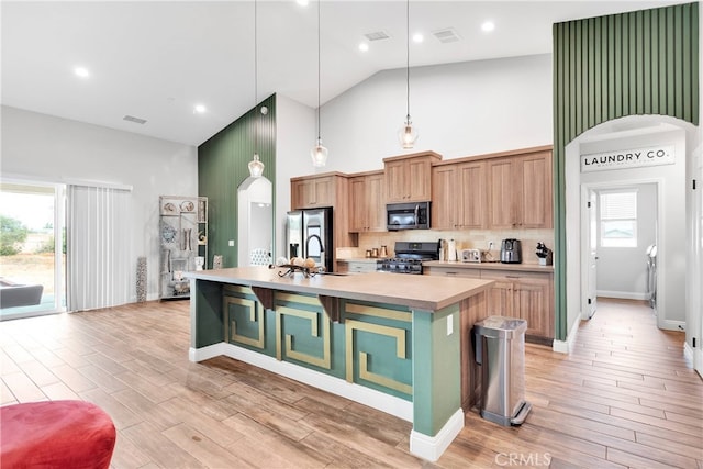 kitchen featuring a spacious island, appliances with stainless steel finishes, high vaulted ceiling, and a wealth of natural light