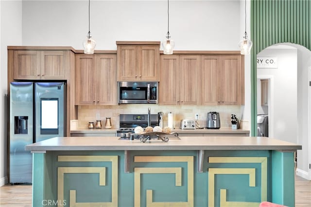 kitchen featuring appliances with stainless steel finishes, a kitchen island with sink, and tasteful backsplash