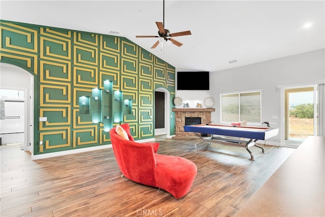 interior space with ceiling fan, a fireplace, hardwood / wood-style floors, and high vaulted ceiling