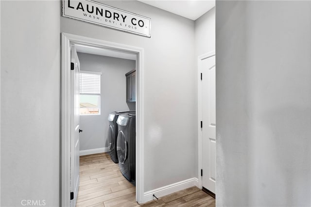 laundry room with cabinets, light wood-type flooring, and washer and clothes dryer