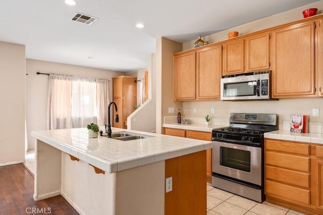 3688 Alhambra Ln, Perris, CA 92571 - kitchen featuring appliances with stainless steel finishes, a center island with sink, tile countertops, and recessed lighting