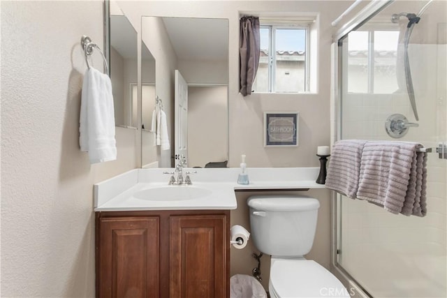 bathroom with vanity, a shower with shower door, and toilet