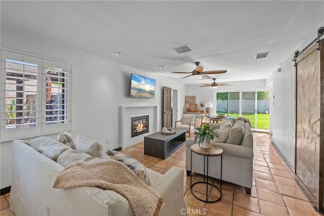 tiled living room with a barn door and ceiling fan