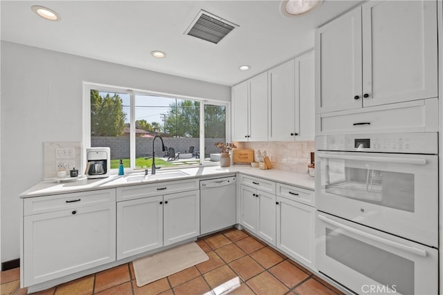 kitchen featuring sink, white cabinets, decorative backsplash, white appliances, and light tile patterned floors