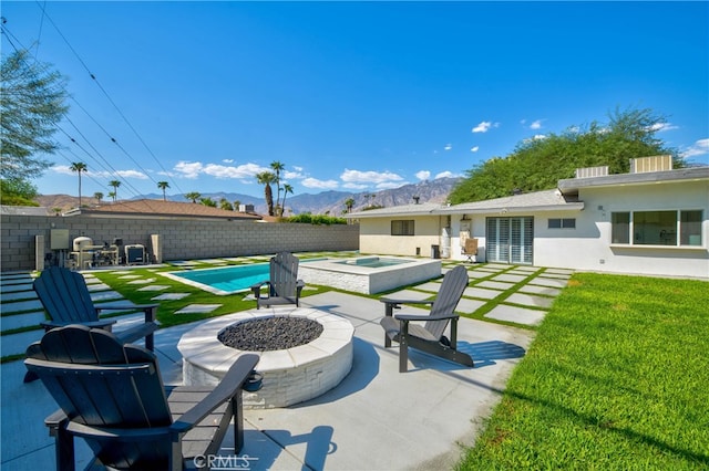 view of patio / terrace with a fire pit, a pool with hot tub, and a mountain view