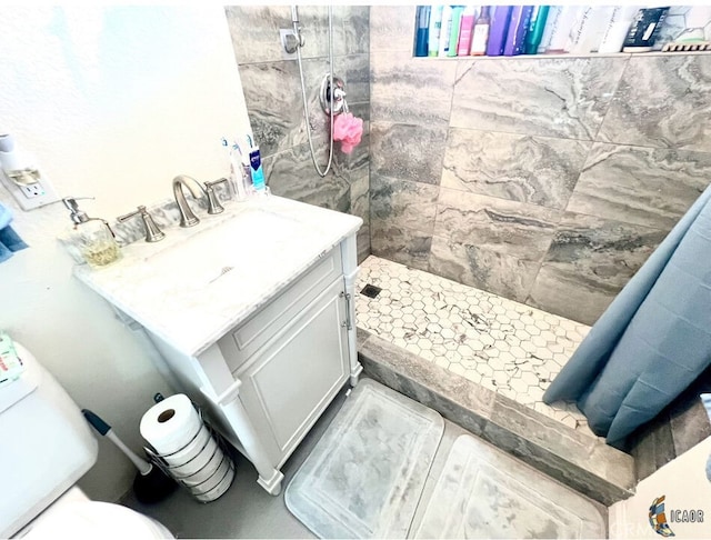 bathroom featuring a tile shower, vanity, and toilet