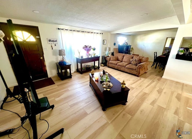 living room featuring a textured ceiling, lofted ceiling, and light wood-type flooring