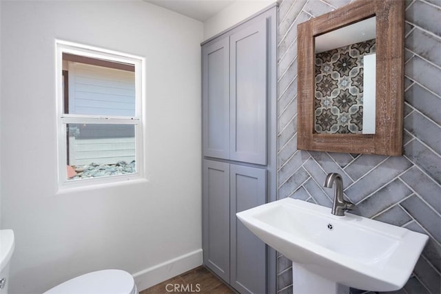 bathroom featuring decorative backsplash, sink, and toilet