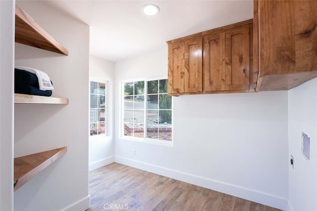 laundry room featuring cabinets, light wood-type flooring, and electric dryer hookup