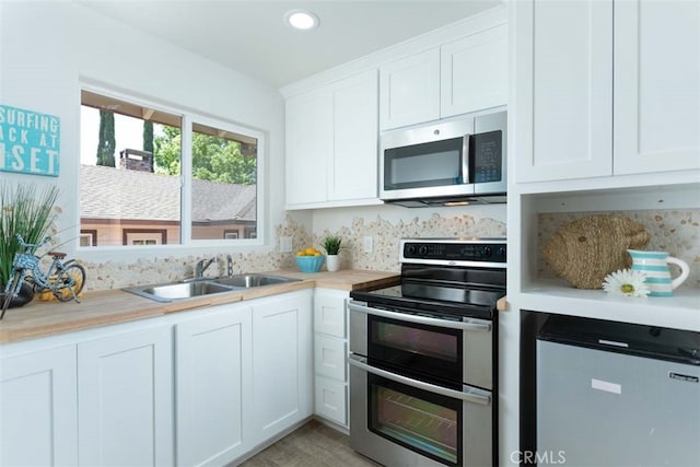 kitchen with appliances with stainless steel finishes, sink, and white cabinets