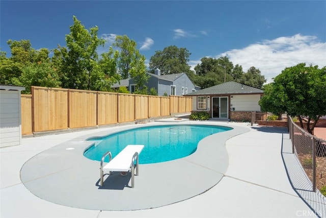 view of pool with a diving board and a patio area