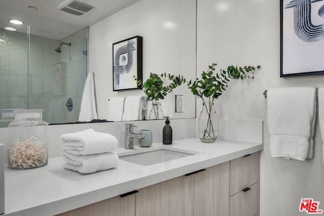 bathroom with a tile shower and vanity