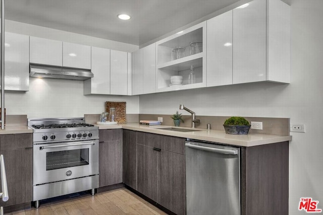 kitchen with light hardwood / wood-style floors, sink, ventilation hood, white cabinets, and appliances with stainless steel finishes