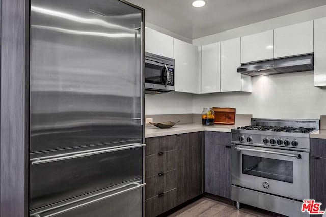 kitchen with dark brown cabinetry, white cabinets, wood-type flooring, ventilation hood, and high quality appliances