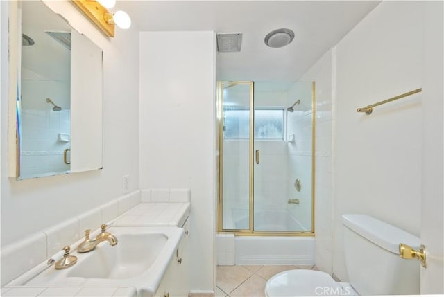 full bathroom featuring toilet, bath / shower combo with glass door, vanity, and tile patterned floors