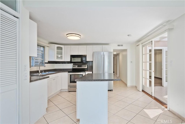 kitchen featuring light tile patterned floors, stainless steel appliances, a kitchen island, white cabinets, and sink