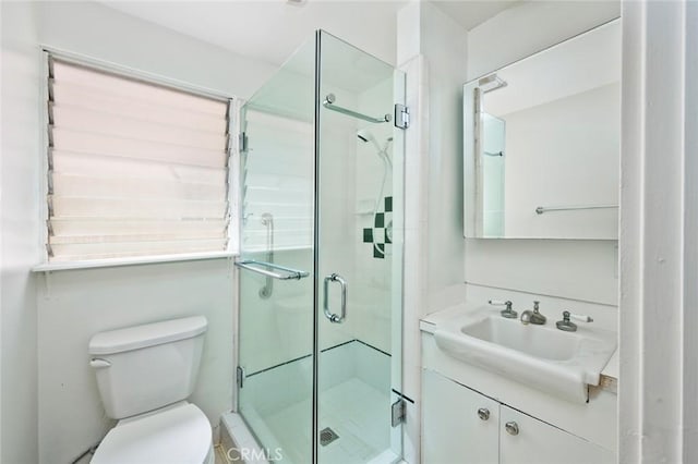 bathroom featuring toilet, a shower with shower door, and vanity