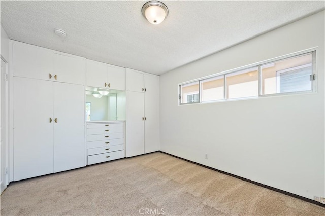 unfurnished bedroom featuring light colored carpet, a textured ceiling, and a closet