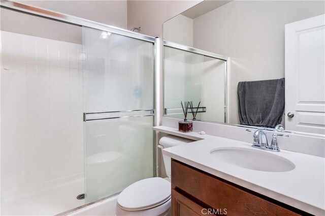 bathroom with vanity, a shower with shower door, and toilet