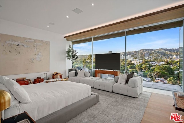 bedroom with a wall of windows and light hardwood / wood-style flooring