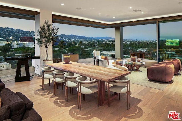 dining area featuring a mountain view, floor to ceiling windows, light hardwood / wood-style floors, and a healthy amount of sunlight