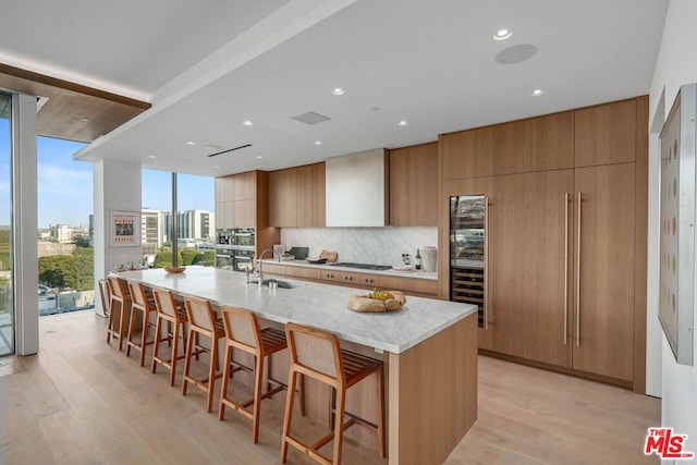 kitchen with light hardwood / wood-style floors, a kitchen bar, a spacious island, and gas cooktop