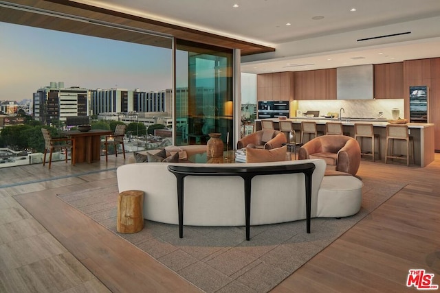 living room featuring light wood-type flooring, floor to ceiling windows, and sink