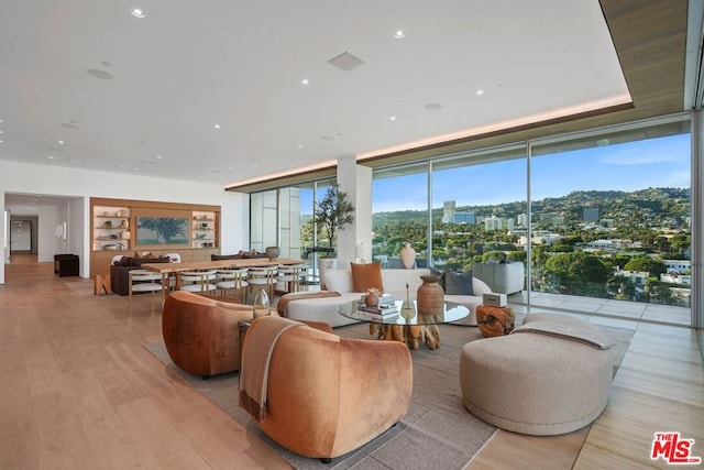 living room featuring a wall of windows and light hardwood / wood-style flooring