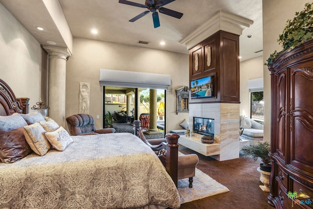 carpeted bedroom with decorative columns, a tiled fireplace, ceiling fan, and access to exterior