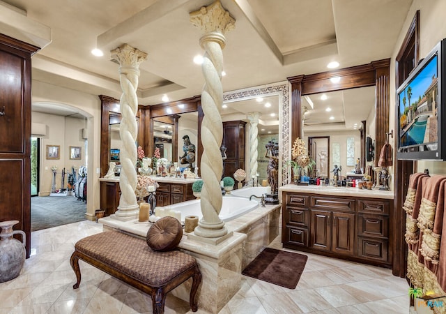 bathroom featuring vanity, a tray ceiling, ornate columns, and a bath