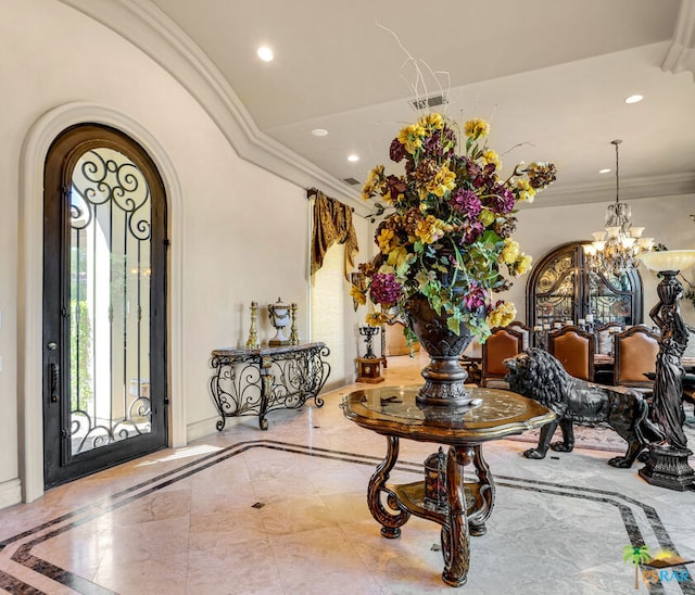 entrance foyer with ornamental molding and a chandelier