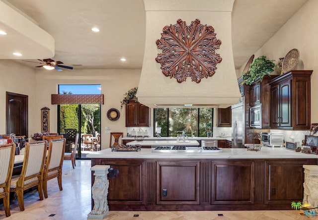 kitchen with built in appliances, tasteful backsplash, kitchen peninsula, dark brown cabinetry, and ceiling fan