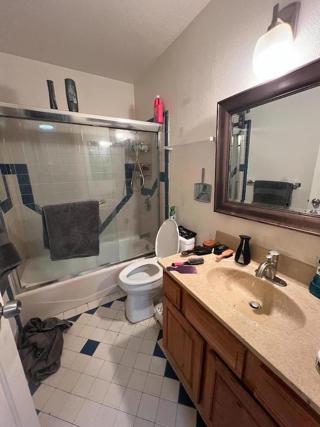 full bathroom featuring enclosed tub / shower combo, vanity, a textured ceiling, tile patterned floors, and toilet