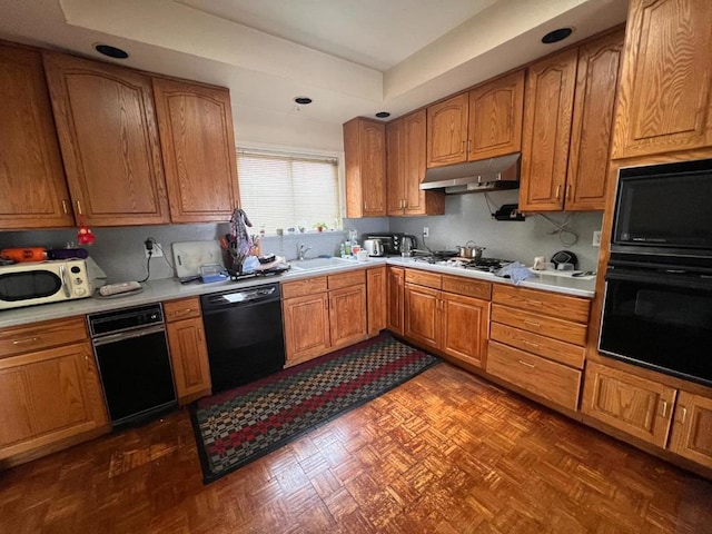 kitchen with a tray ceiling, sink, dark parquet floors, and black appliances