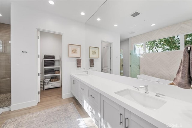 bathroom with hardwood / wood-style flooring, vanity, and a shower