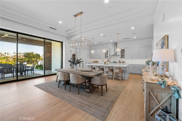 dining area featuring a raised ceiling, an inviting chandelier, and light hardwood / wood-style flooring