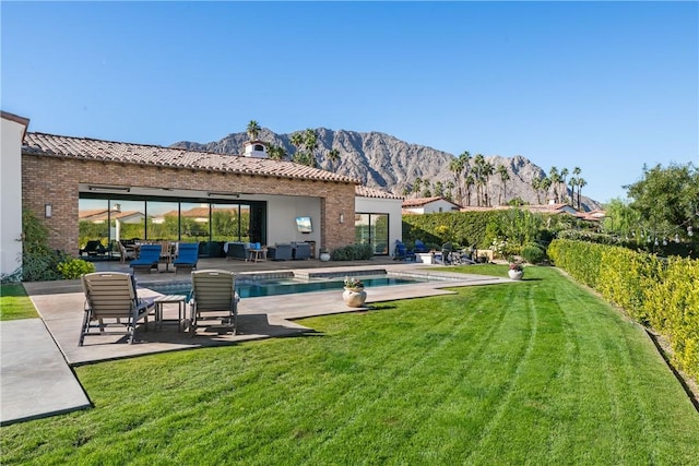 rear view of property featuring a yard, a fenced in pool, a patio, and a mountain view