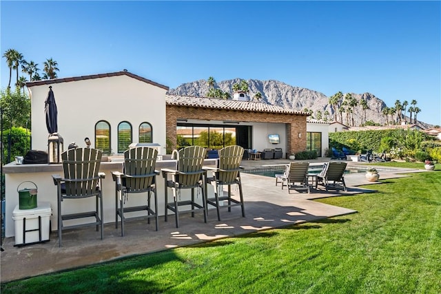 back of house featuring a lawn, exterior bar, a fenced in pool, a mountain view, and a patio area