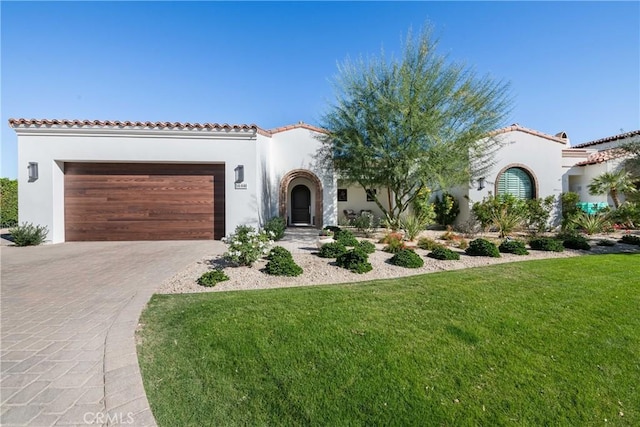 mediterranean / spanish-style home featuring a garage and a front lawn